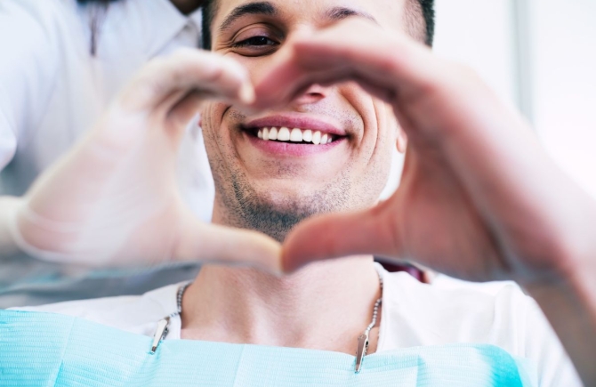 Man maakt hartje met handen in tandartsstoel