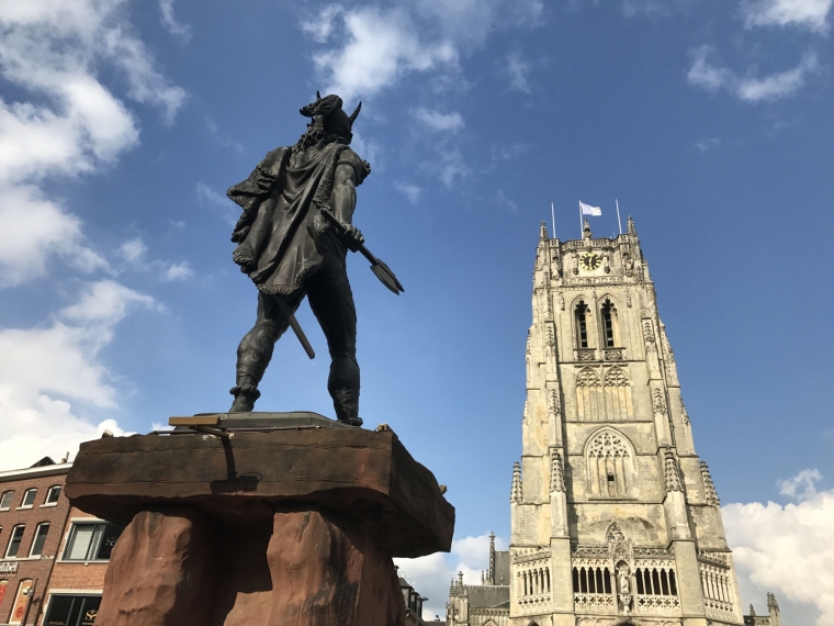standbeeld van Ambiorix dat naar de Onze-Lieve-Vrouwebesiliek kijkt